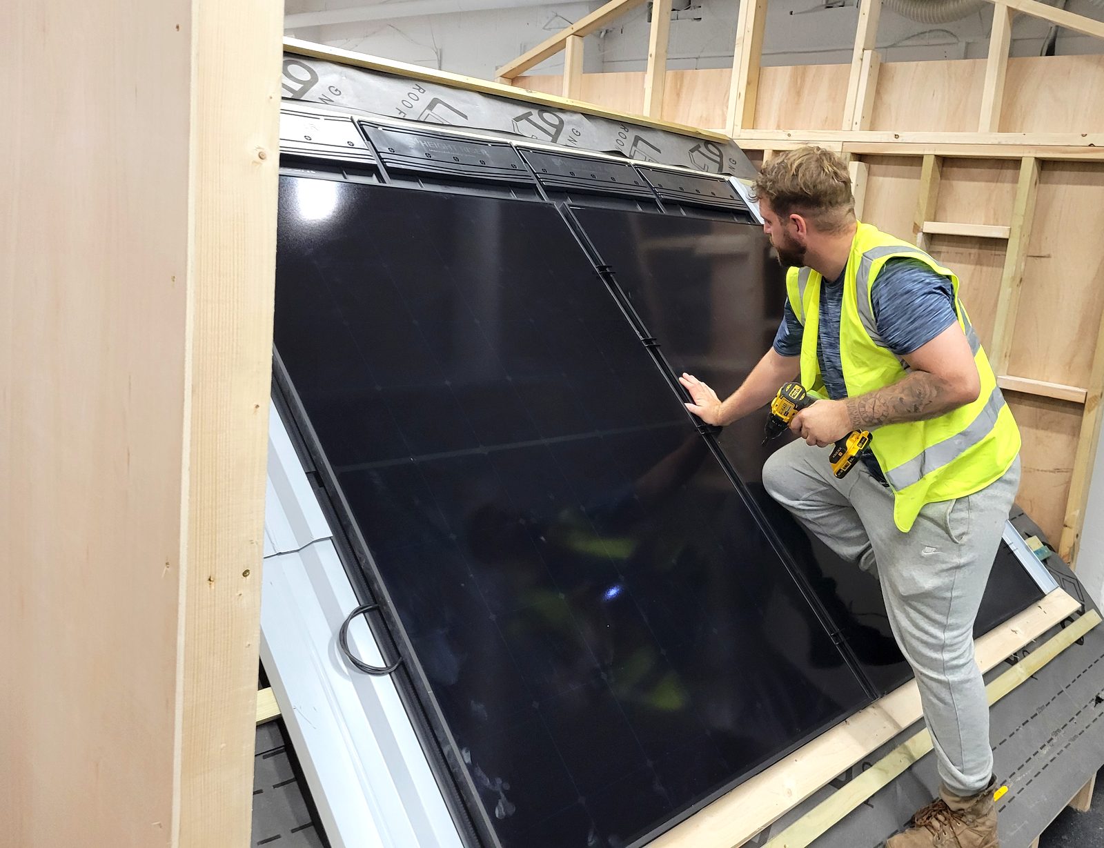 Learner securing a solar panel into an in-roof tray system during a Cornerstone solar PV course