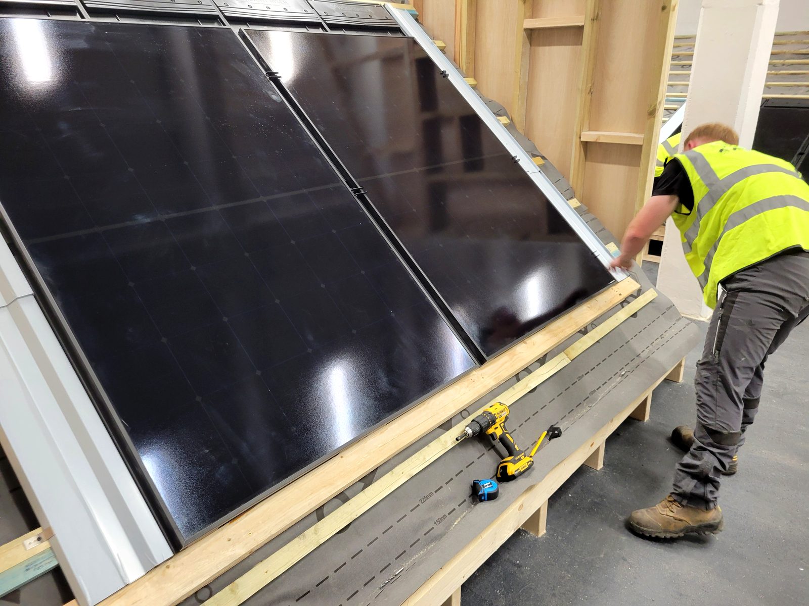 Trainee fitting solar panels into an in-roof mounting tray on the training rig at Cornerstone, Birkenhead
