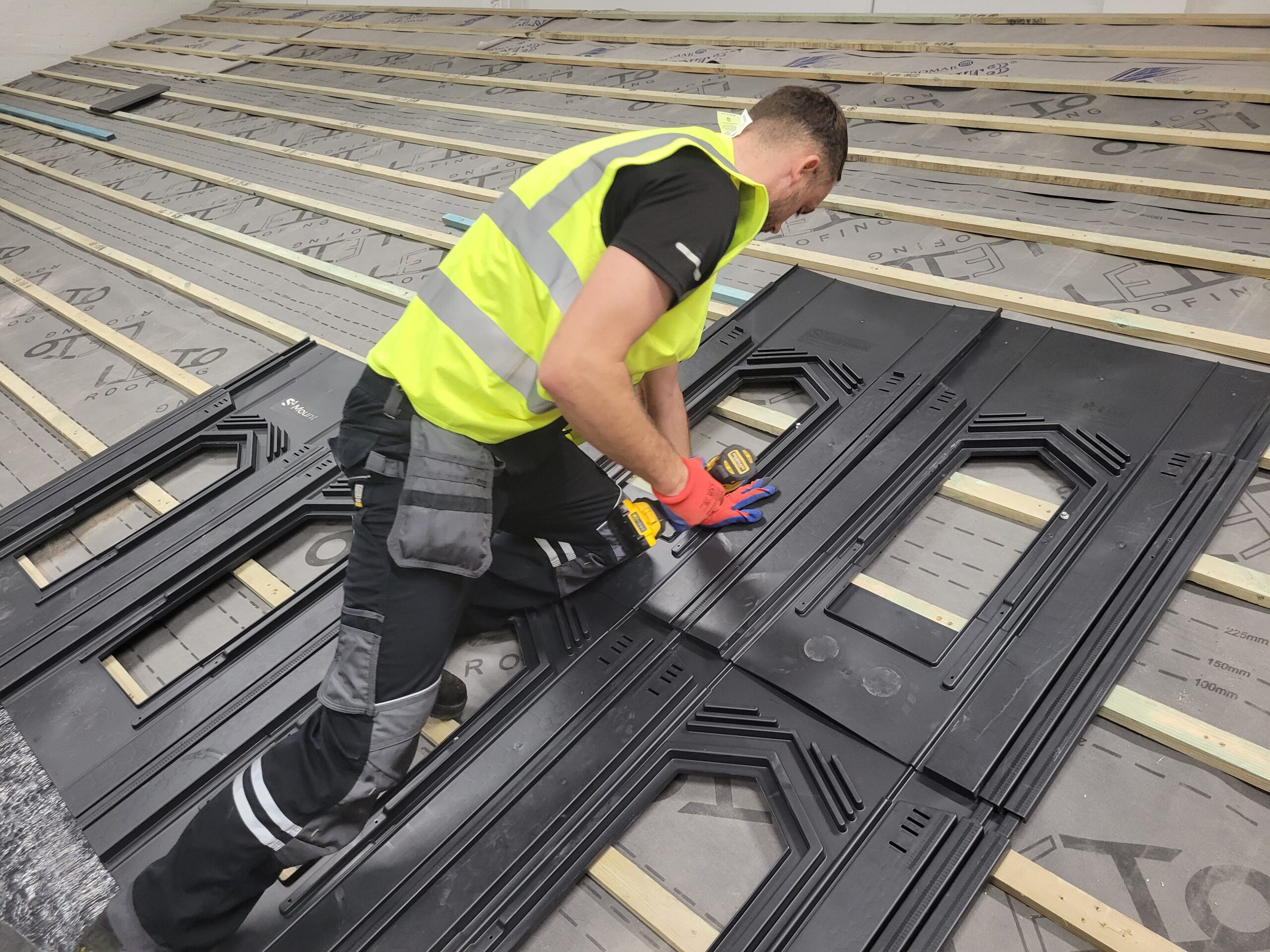 Learner fitting an S4 in-roof solar tray system onto roof battens at Cornerstone Vocational Training, Birkenhead