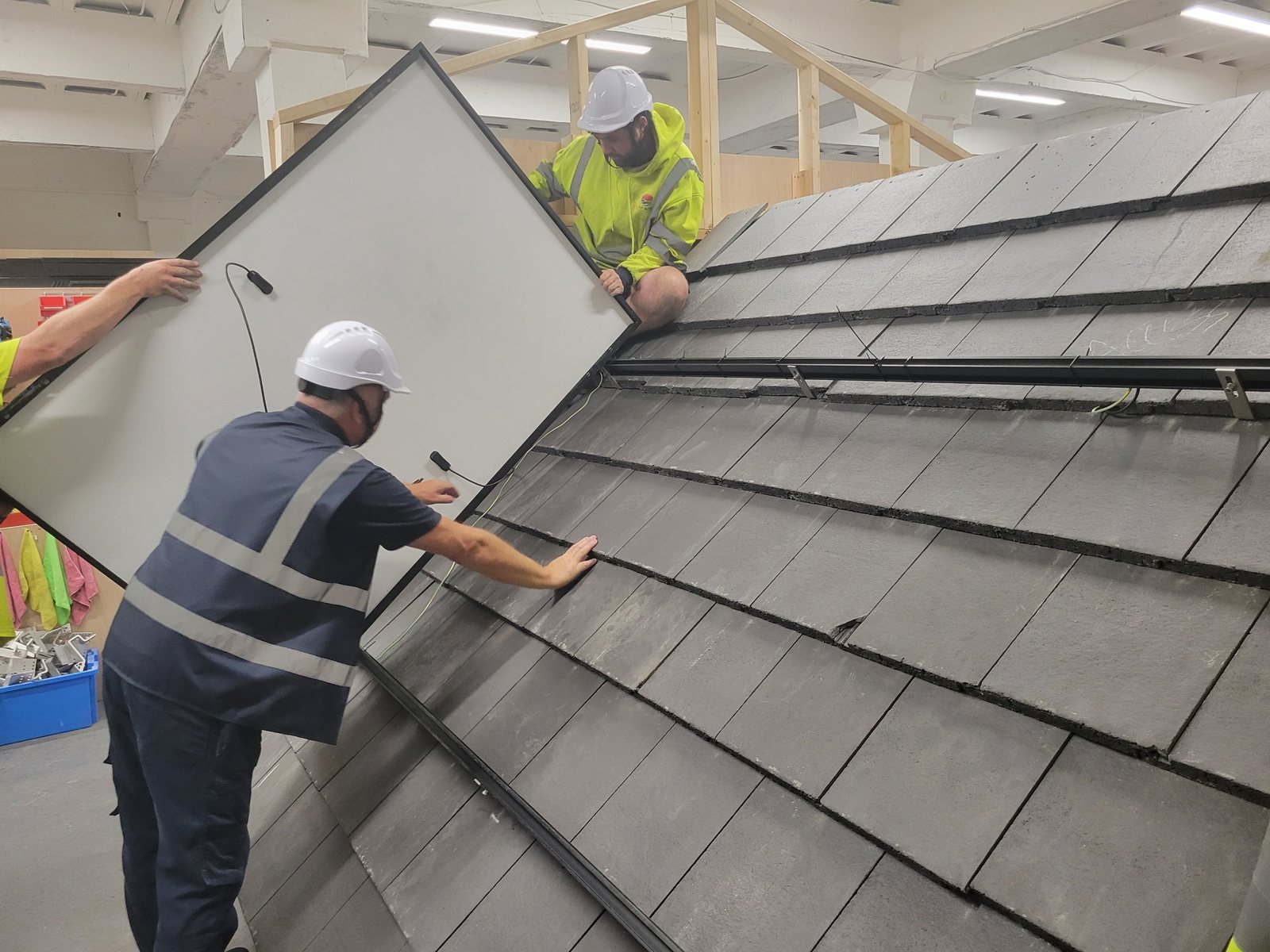Solar panel being lowered onto the on-roof mounting rails above a slate roof on the training rig at Cornerstone Vocational Training, Birkenhead